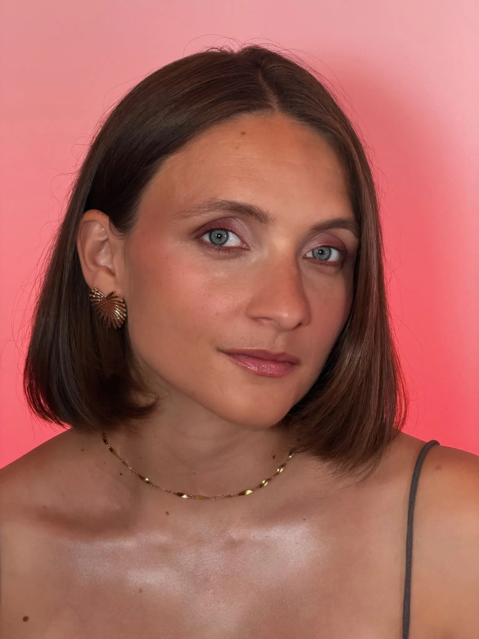 Portrait beauté sur fond rose : carré brun lisse, fard rosé irisé et teint lumineux